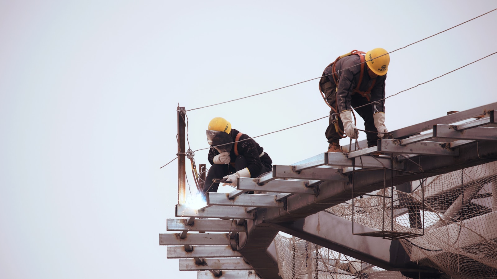 man in black jacket and yellow hard hat standing on top of building during daytime, builders risk